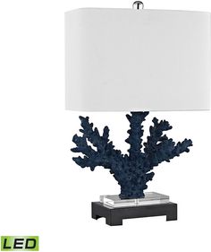 a blue coral lamp with a white shade on the base and an acrylic box underneath it