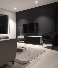 a black and white living room with two chairs, a couch and a television on the wall