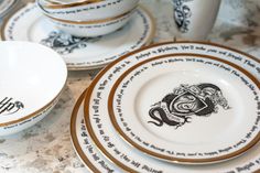 a table topped with white and gold plates covered in black lettering on it's sides