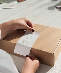 a woman is opening a box with a piece of paper in it and her hand on top of the card