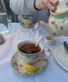 a person pouring tea into a cup on a table