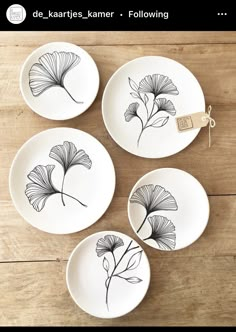 four plates with flowers painted on them sitting on a wooden table next to a tag