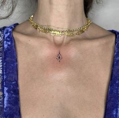 a woman wearing a gold choker with a diamond tattoo on her chest