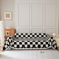 a black and white checkered couch sitting on top of a hard wood floor next to a wall