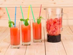 three glasses filled with drinks and straws next to each other on a wooden table