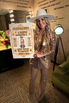 a woman in a cowboy hat holding up a sign with the name of her band