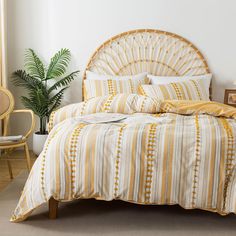 a bed with yellow and white striped comforter next to a potted palm tree