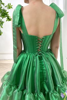 This gorgeous green sparkly organza tiered dress with tie straps is the perfect blend of elegance and fun. The corset style bodice provides a flattering fit while the tiered organza skirt adds a touch of whimsy. Whether you're attending a special event or just want to stand out, this dress is sure to make a statement. Bust and Skirt with full lining. 100% Polyester 100% Recycled polyester lining Concealed zip at center back Imported Green Dress With Corset Back And Fitted Bodice, Green Corset Back Dress For Prom, Green Corset Dress With Corset Back For Prom, Green Prom Dress With Lace-up Back, Green Corset Back Dress For Party, Green Corset Dress With Sweetheart Neckline For Party, Fitted Green Corset Dress With Spaghetti Straps, Green Corset Dress With Spaghetti Straps, Green Fitted Corset Dress With Spaghetti Straps