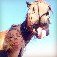 a woman standing next to a horse with it's mouth open