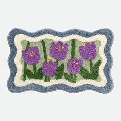 a door mat with purple flowers and green leaves in the center on a white background