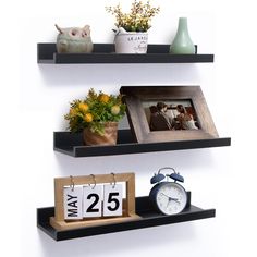 two black floating shelves with pictures and clocks