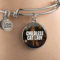 Get our Childless Cat Lady Bracelet today and be amazed by its quality and style! Made with durable surgical steel and the option for 18k gold finish, this jewelry item is the ultimate keepsake for yourself or your loved ones. Plus, we offer a 100% Happiness Guarantee - if for any reason you're not completely satisfied, just let us know and we'll make it right. Your satisfaction is our top priority. Product Dimensions➜ Luxury Bangle: 7-9" (18-22.75cm). This bangle features a stretchable design that allows it to expand as you slide it onto your wrist, then it effortlessly returns to its original shape.➜ Circle Pendant: 23.5mm x 23.5mm. Stainless Steel Friendship Bangle, Hypoallergenic Round Stainless Steel Jewelry, Nickel-free Adjustable Surgical Steel Jewelry, Adjustable Nickel-free Surgical Steel Jewelry, Nickel-free Round Surgical Steel Jewelry, Personalized Hypoallergenic Stainless Steel Jewelry, Hypoallergenic Stainless Steel Jewelry For Personalized Gifts, Customizable Stainless Steel Jewelry, Stainless Steel Charm Bracelet For Friendship