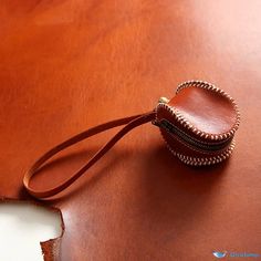 a brown leather case sitting on top of a wooden table next to a white piece of paper