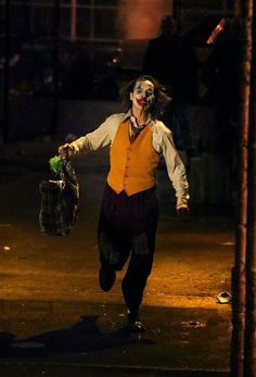 a man dressed as the joker running down a street