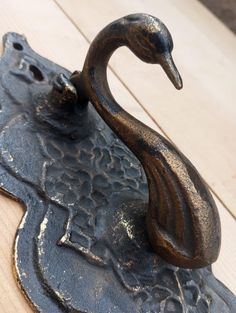 a metal object that looks like a duck sitting on top of a piece of wood