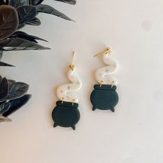 two pairs of black and white earrings on top of a table next to some plants