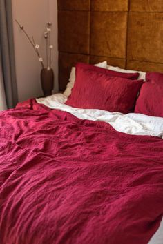 the bed is made with red linens and pillows