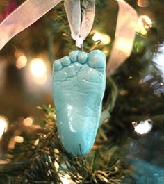 an ornament hanging from a christmas tree with the foot of a baby's feet