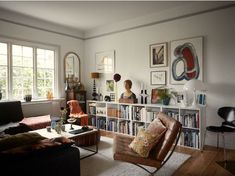 a living room filled with furniture and bookshelves next to a window covered in pictures