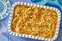 a casserole dish with chicken and noodles in it on a blue table cloth