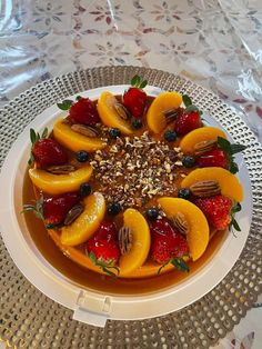 a plate with fruit and nuts on it sitting on top of a white table cloth