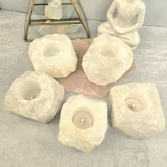 four white candles sitting on top of a table next to a buddha figurine