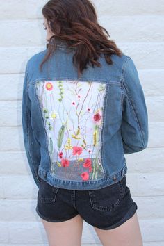 the back of a woman's jean jacket with flowers on it