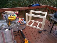 a table with tools on it sitting on a deck next to a chair and other items