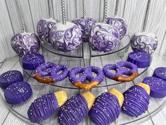 purple and white decorated doughnuts on a glass tray