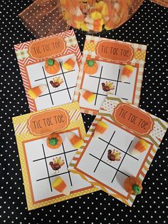 four halloween tic tac toe game cards with candy corn on them and a trick bag in the background