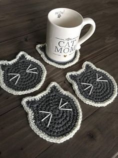 three crocheted coasters with cats on them and a coffee cup in the middle