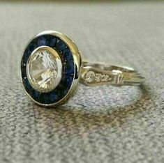 a gold ring with blue and white stones on the side, sitting on top of a table