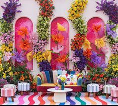 a room filled with lots of colorful furniture and flowers on the wall behind it,