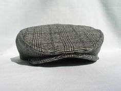 a gray and black plaid hat sitting on top of a white table