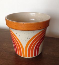 an orange and white bowl sitting on top of a wooden table