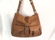 Gorgeous caramel brown leather satchel shoulder bag, excellent condition no scuffing or damage to the leather, lining also clean and unmarked.  Two front buckled pockets with a further buckle and magnetic snap to close the flap.  Short bridle-style shoulder strap, so the bag can be worn underarm or held by hand or crook of the arm.  The leather is thick but still soft and supple with a pebble leather finish.  Lined in caramel brown lining with a leather topped divider, 90s style phone pouch and Saddle Purse, Brown Leather Satchel, Leather Finish, Caramel Brown, Phone Pouch, Top Handle Bags, 90s Style, Leather Satchel, Leather Top