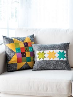 two pillows sitting on top of a white couch