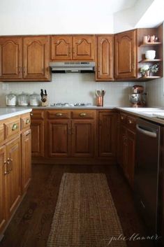 a kitchen with wooden cabinets and white counter tops on a rug in front of the sink