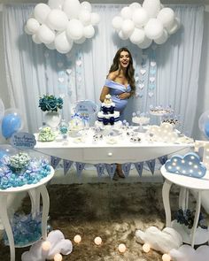 a woman standing in front of a table with blue and white decorations