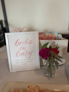 there is a card that says books for baby next to a vase with pink flowers