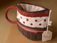 a red and white polka dot coffee cup with a tag on the handle, sitting on a wooden surface