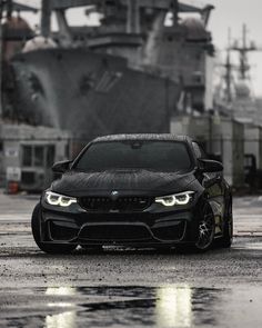 a black car parked in front of a large ship