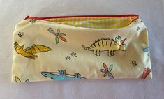 Small zipper pouch in fun dinosaur pattern. Can be used as a pencil case or to hold other small items, like snacks or toys! Made with cotton fabric, lined with yellow gingham, and measures approximately 9x4 inches. Sewn in Peabody, Massachusetts. Yellow Rectangular Pencil Case With Pen Holders, Yellow Pouch Pencil Case As Gift, Yellow Rectangular Zipper Pouch Pencil Case, Yellow Pouch Pencil Case Gift, Yellow Rectangular Zipper Pencil Case, Yellow Rectangular Pencil Case With Zipper, Yellow Pencil Case With Pen Holders For Everyday Use, Yellow Pencil Case For Everyday Use, Yellow Pencil Case With Pen Holders