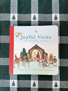 the joyful noise christmas story book on a green and white checkered tablecloth