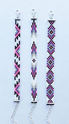 two bracelets made out of beads and chains on a white surface, one is pink and the other is blue