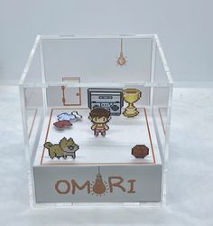 a clear box with some pixelated items inside it on a white surface and the words omri written in small letters