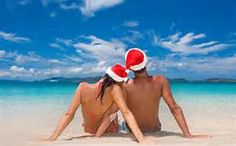 a man and woman sitting on top of a sandy beach under a blue sky with the words, we wish you a belize navidad