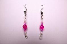 pink and white beaded earrings with silver hooks hanging from earwires on a plain surface