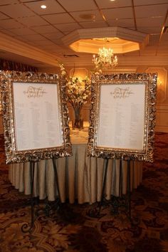 two framed menus sitting on top of a table in front of a chandelier