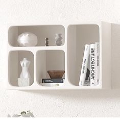 a white shelf with books and vases on it